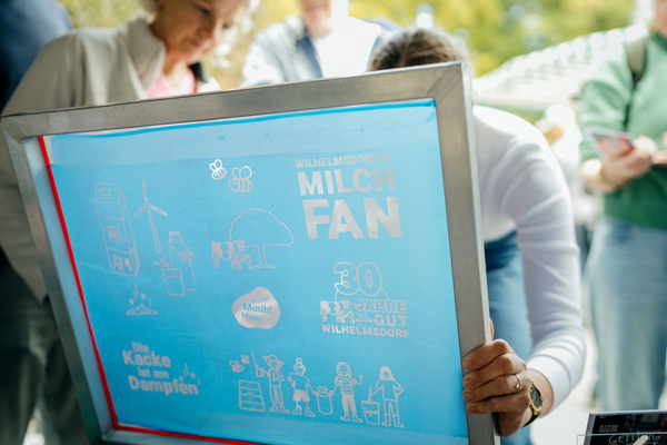 KI generiert: Ein Siebdruckrahmen mit Grafiken und Texten, darunter "WILHELMSDORFER MILCHFAN" und "30 JAHRE GUT WILHELMSDORF".