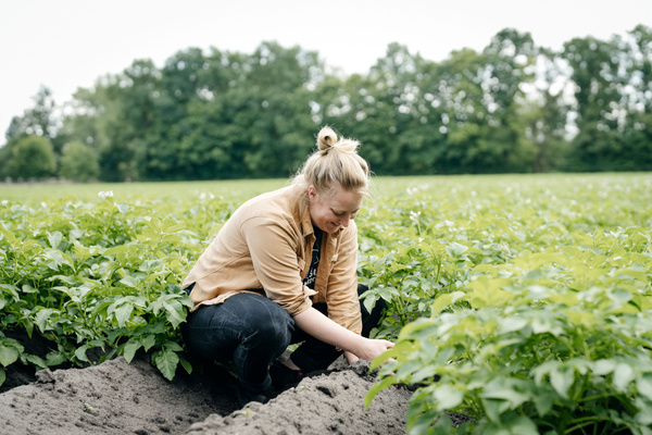 Katrin greift bei einer Käseverkostung zu einem Stück Käse und hat eine passende Weinbegleitung in der Hand.