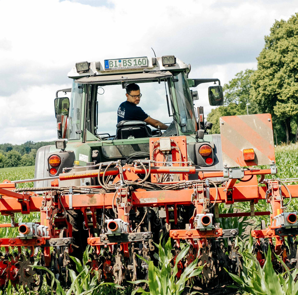 KI generiert: Ein Landwirt fährt einen Traktor mit landwirtschaftlichem Gerät durch ein Feld.