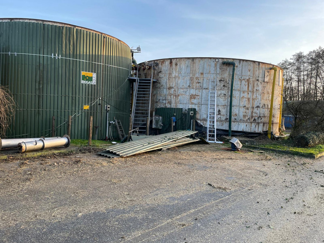 KI generiert: Zwei Biogastanks mit beschädigter Verkleidung, Leitern und Rohren im Freien. Text: "BIOGAS".