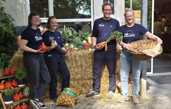 KI-generierte Beschreibung: Drei Personen präsentieren Ökokisten mit Gemüse und Brot.