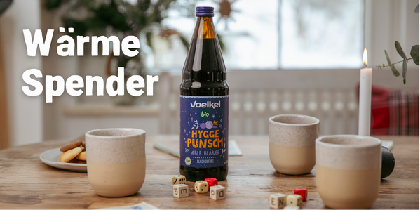 KI generiert: Flasche Voelkel Hygge Punsch auf Tisch mit Tassen. Text: "Wärme Spender".