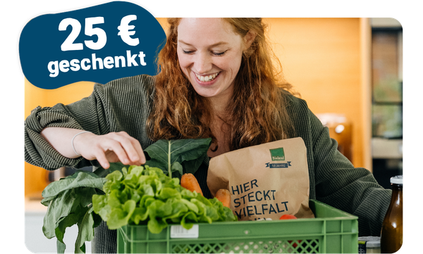 KI generiert: Eine Frau hält einen Korb mit Gemüse und ein Schild mit Text. "Hier steckt Vielfalt" und "25 € geschenkt".