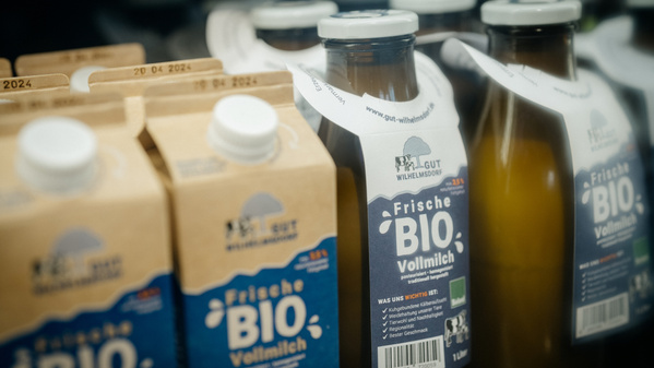 KI generiert: Bio-Milchverpackungen im Regal. Text: "Frische BIO Vollmilch", "Gut Wilhelmsdorf".