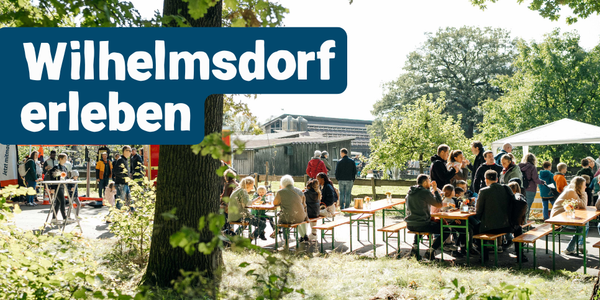 KI generiert: Menschen sitzen und stehen an Tischen im Freien bei Sonnenschein. Text: „Wilhelmsdorf erleben".
