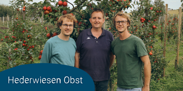 KI generiert: Das Bild zeigt drei Personen, die vor einer Obstplantage mit Apfelbäumen stehen. Im Vordergrund ist der Schriftzug "Hederwiesen Obst" zu sehen.