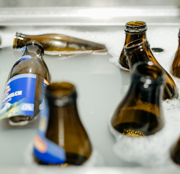 KI generiert: Leere Flaschen mit Etiketten in seifigem Wasser zur Reinigung eingeweicht.