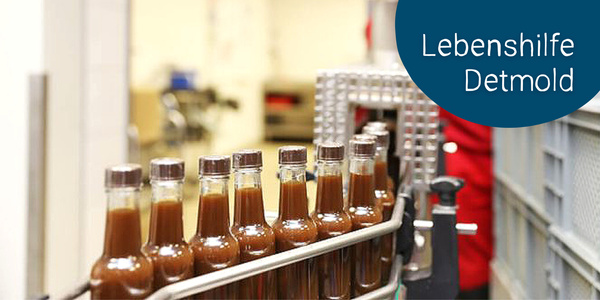 KI generiert: Das Bild zeigt eine Produktionslinie mit mehreren Glasflaschen, die mit einer braunen Flüssigkeit gefüllt sind. Im Bild ist auch ein Text mit der Aufschrift "Lebenshilfe Detmold" sichtbar.