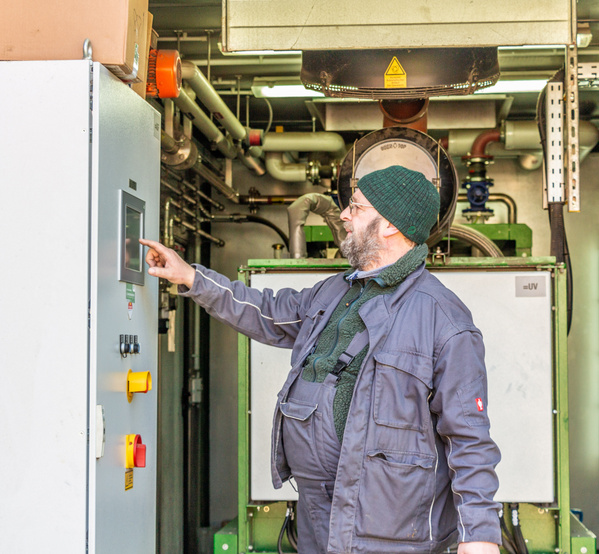 KI generiert: Ein Mann bedient ein großes Steuergerät in einer industriellen Umgebung.